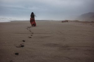 footprints in the sand girl walking along the california coastline gold bluffs beach california wedding photographer
